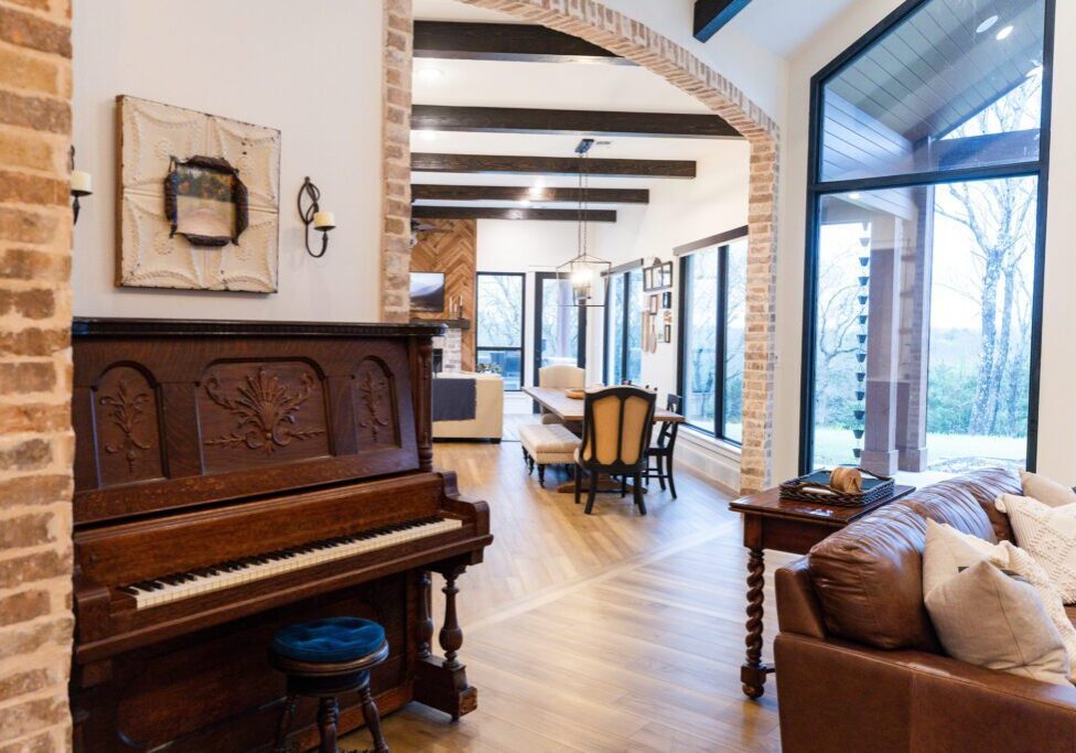 Open living room with piano and dining table.